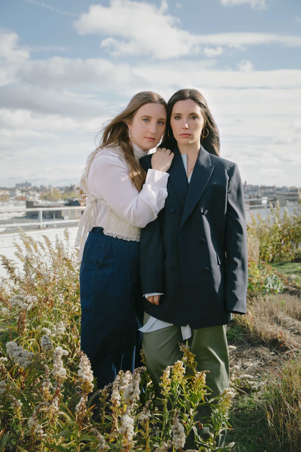 olivia and emma stand on a landscaped roof with a view of new york city