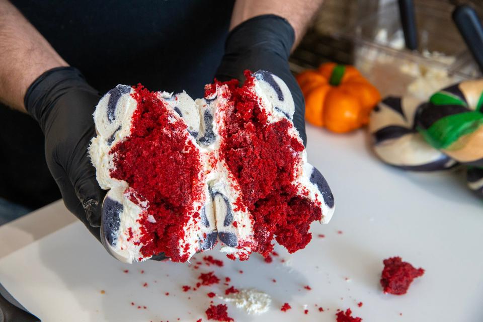 Alex Berkowitz, co-owner of The Bagel Nook, prepares The Scream overload bagel, a black and white hand rolled bagel with sweet cream cream cheese and a red velvet muffin stuffed in the middle.