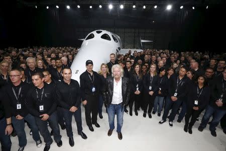 Richard Branson (C) poses after unveiling the new SpaceShipTwo, a six-passenger two-pilot vehicle meant to ferry people into space that replaces a rocket destroyed during a test flight in October 2014, in Mojave, California, United States, February 19, 2016. REUTERS/Lucy Nicholson/Files