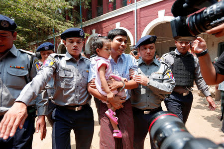 Detained Reuters journalist Kyaw Soe Oo holding his daughter is escorted by police after a court hearing in Yangon, Myanmar March 28, 2018. REUTERS/Stringer