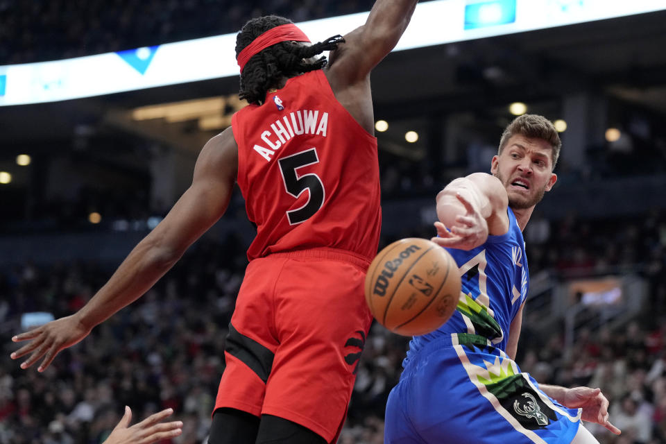 Milwaukee Bucks centre Meyers Leonard (3) makes a behind-the-back pass beside Toronto Raptors forward Precious Achiuwa (5) during first half an NBA basketball game in Toronto, Sunday, April 9, 2023. (Frank Gunn /The Canadian Press via AP)