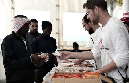 Migrants receive food on the deck of MV Aquarius, a search and rescue ship run in partnership between SOS Mediterranee and Medecins Sans Frontieres on their way to Spain June 15, 2018. Karpov / SOS Mediterranee/handout via REUTERS