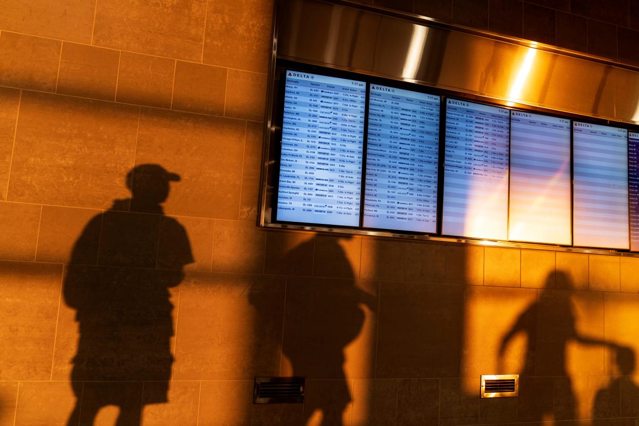 The sunrise casts shadows of travelers moving past gate information screens at Detroit Metropolitan Airport on Labor Day, Monday, Sept. 4, 2023, in Detroit. (AP Photo/David Goldman)