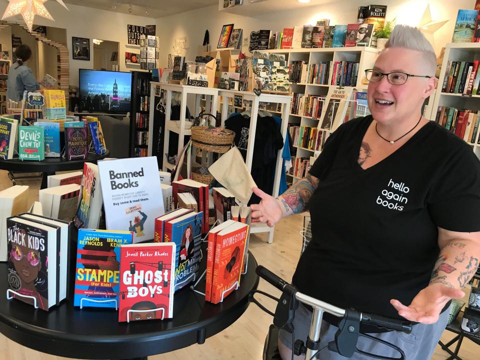 MerryBeth Burgess, an owner of Hello Again Books, stands beside a display of books Moms for Liberty chapters have requested removed from Florida public school libraries