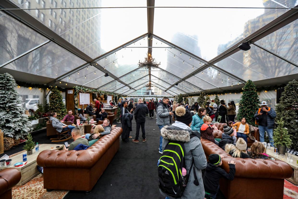 People warm up in the Cadillac Lodge, operated by the Iconic Collection, after shopping at more than a dozen local businesses at the Downtown Detroit Markets at Cadillac Square in downtown Detroit on Wednesday, Nov. 22, 2023. The local business markets, which will be open until Jan. 7, are funded by Gilbert Family Foundation and operated with support from Bedrock and Tech Town.