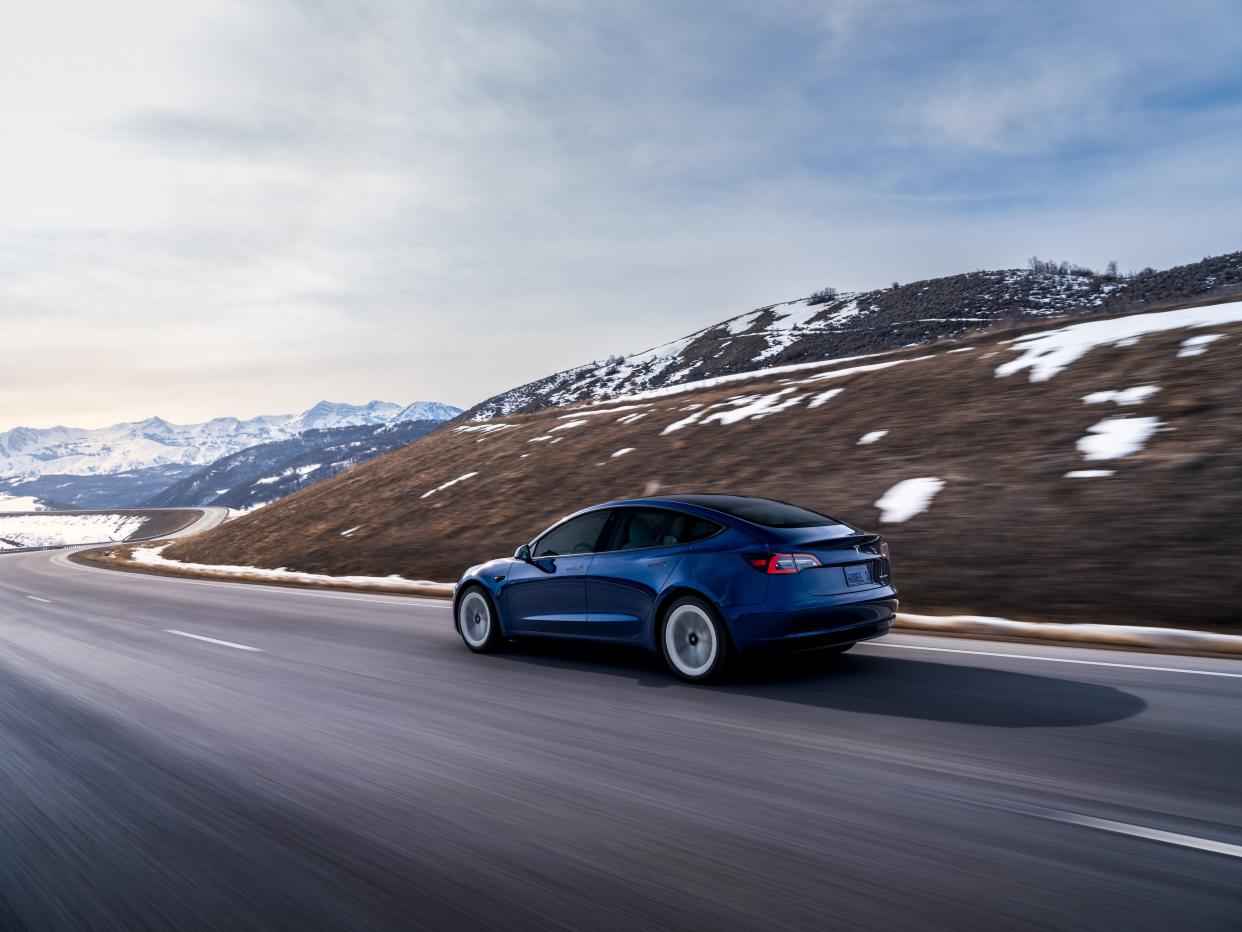 Blue Tesla Model 3 driving in snow