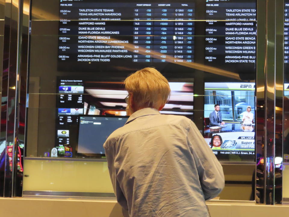 A customer checks the odds board in the sports book at the Ocean Casino Resort in Atlantic City N.J. on Feb. 6, 2023. Americans have bet over $220 billion on sports with legal gambling outlets in the five years since the U.S. Supreme Court cleared the way for all 50 states to offer it. (AP Photo/Wayne Parry)