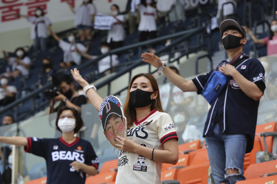 Fans wearing face masks to help protect against the spread of the new coronavirus cheer during the KBO league game between Doosan Bears and LG Twins in Seoul, South Korea, Sunday, July 27, 2020. Masked fans hopped, sang and shouted cheering slogans in baseball stadiums in South Korea on Sunday as authorities began bringing back spectators in professional sports games amid the coronavirus pandemic. (AP Photo/Ahn Young-joon)