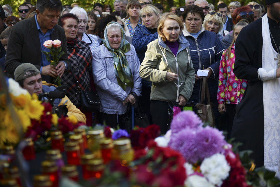 People place flowers by a national memorial during a ceremony commemorating an attack on a vocational college, in Kerch, Crimea, Thursday, Oct. 18, 2018. An official says that authorities on the Crimean Peninsula are searching for a possible accomplice of the student who carried out an attack on a vocational school, killing 20 people and wounding more than 50 others. (AP Photo/Sergei Demidov)