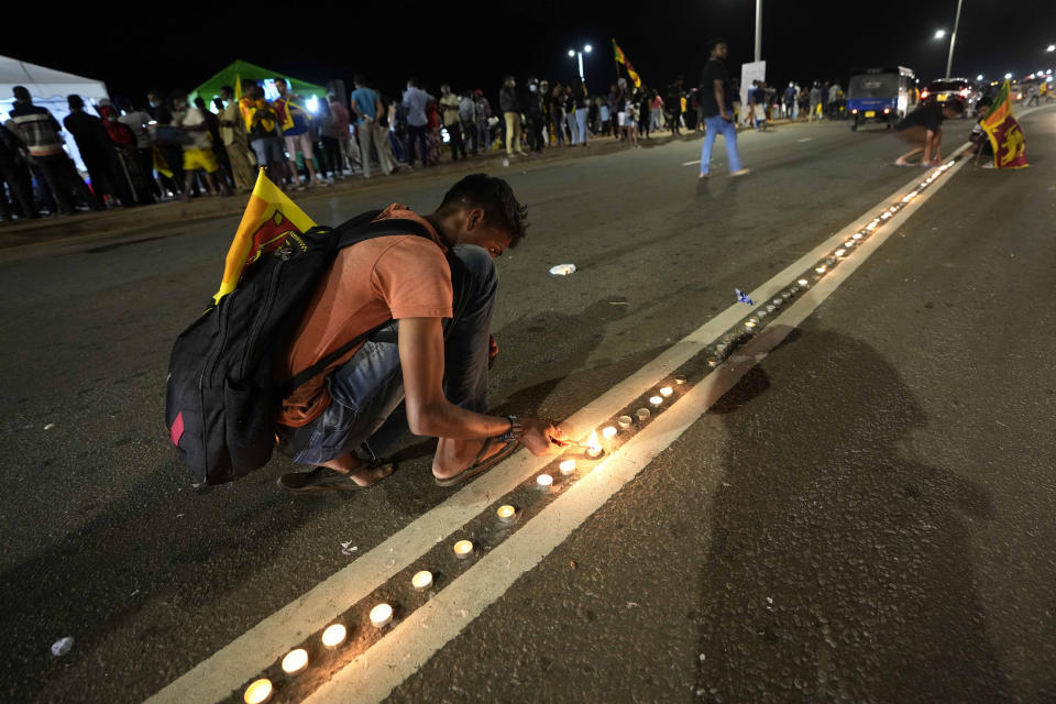 Sri Lankans light candles during a vigil condemning police shooting at protesters in Rambukkana, 90 kilometers (55 miles) northeast of Colombo, at a protest outside the president's office in Colombo, Sri Lanka, Tuesday, April 19, 2022. Sri Lankan police opened fire Tuesday at a group of people protesting new fuel price increases, killing one and injuring 10 others, in the first shooting by security forces during weeks of demonstrations over the country's worst economic crisis in decades. (AP Photo/Eranga Jayawardena)