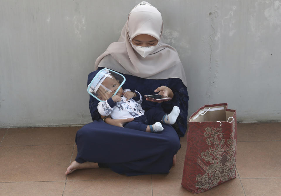 A woman wearing a face mask to curb the spread of coronavirus with her baby attends during an Eid al-Adha prayer at Zona Madina mosque in Bogor, Indonesia,Tuesday, July 20, 2021. Muslims across Indonesia marked a grim Eid al-Adha festival for a second year Tuesday as the country struggles to cope with a devastating new wave of coronavirus cases and the government has banned large gatherings and toughened travel restrictions. (AP Photo/Tatan Syuflana)