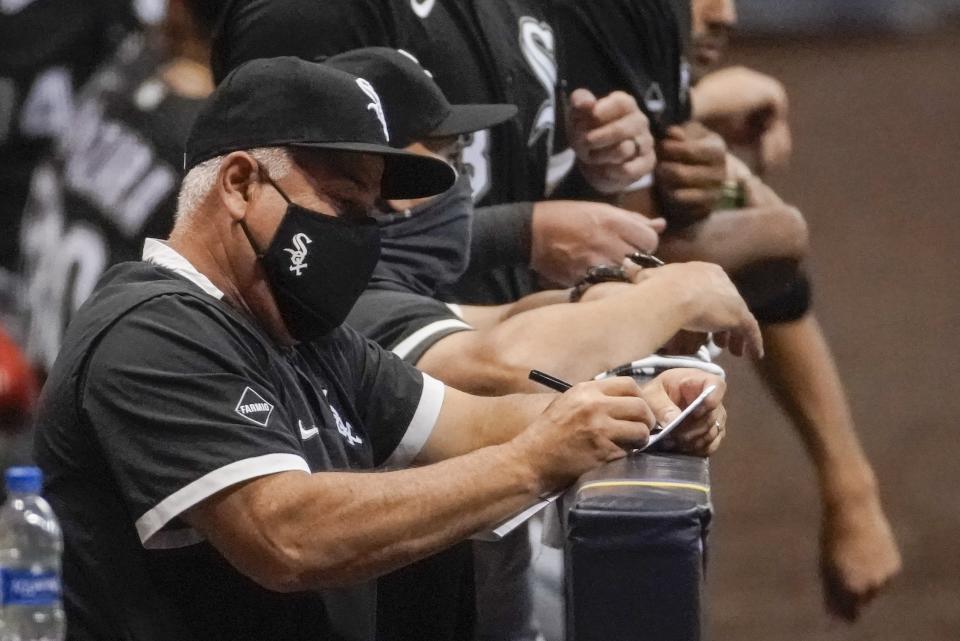 Chicago White Sox manager Rick Renteria takes notes during the seventh inning of a baseball game against the Milwaukee Brewers Monday, Aug. 3, 2020, in Milwaukee. (AP Photo/Morry Gash)