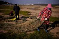 FILE PHOTO: Fishermen recycle shrimp nets on the dried lake bed of Poyang lake, China