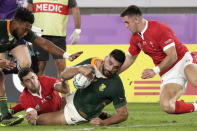 FILE - South Africa's Damian de Allende, center, crashes over to score a try during the Rugby World Cup semifinal at International Yokohama Stadium between Wales and South Africa in Yokohama, Japan, Sunday, Oct. 27, 2019. Scotland forward Dave Cherry is out of the Rugby World Cup in France after slipping on the stairs at the team hotel, banging his head and sustaining a concussion. He isn’t the first rugby player to get hurt in a strange way on his time off. Some of rugby’s tough men have come unstruck grappling with dogs, dishwashers and even an out-of-control fire. (AP Photo/Aaron Favila, File)