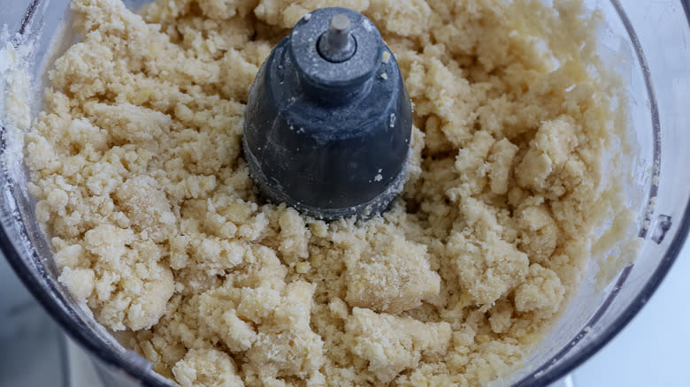 food processor with crumbly dough in it