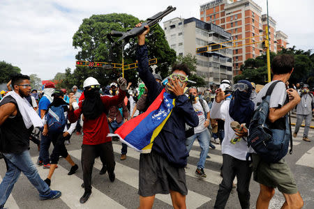 Opposition supporters show a shotgun that they snatched from riot police during a rally against President Nicolas Maduro in Caracas, Venezuela, May 3, 2017. REUTERS/Carlos Garcia Rawlins