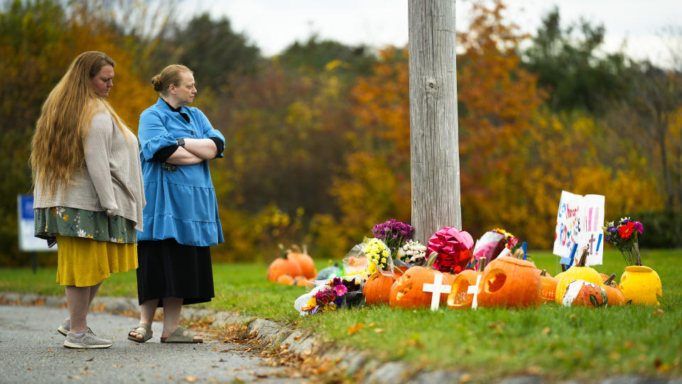 People pay their respects at a makeshift memorial outside a bowling alley, the site of one of this week's mass shootings, Sunday, Oct. 29, 2023, in Lewiston, Maine. A gunman killed multiple people at the bowling alley and a bar in Lewiston on Wednesday. (AP Photo/Matt Rourke)