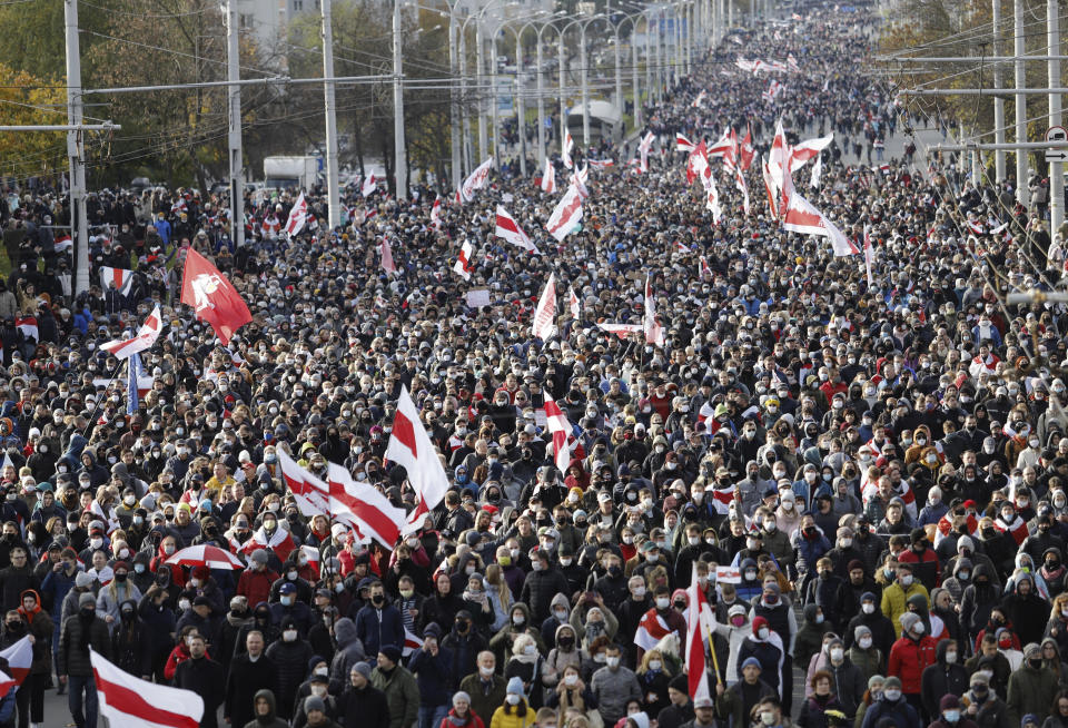 People with old Belarusian national flags march during an opposition rally to protest the official presidential election results in Minsk, Belarus, Sunday, Oct. 18, 2020. Hundreds of thousands of Belarusians have been protesting daily since the Aug. 9 presidential election. (AP Photo)