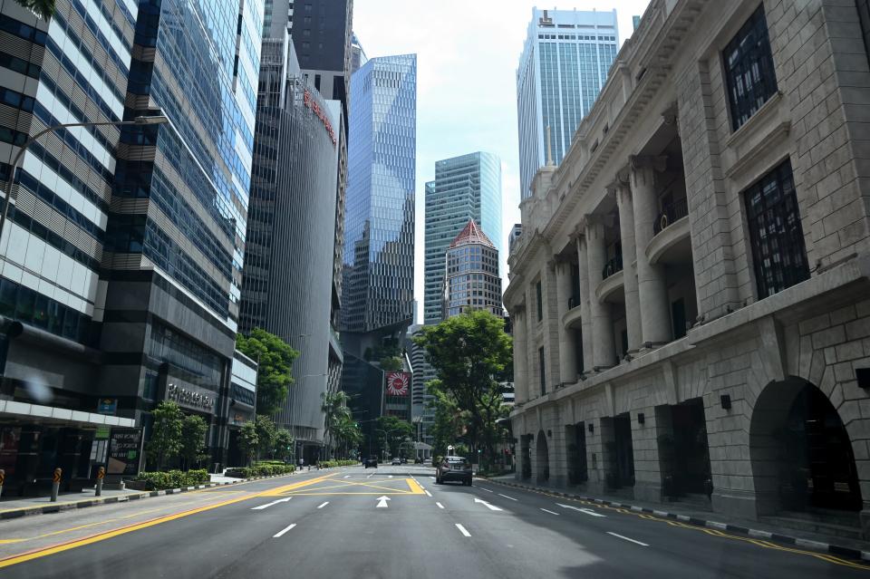 A car drives along an otherwise empty road in the financial district of Singapore on April 24, 2020, as the country undergoes a partial lockdown to fight the spread of the COVID-19 novel coronavirus. (Photo by Roslan RAHMAN / AFP) (Photo by ROSLAN RAHMAN/AFP via Getty Images)