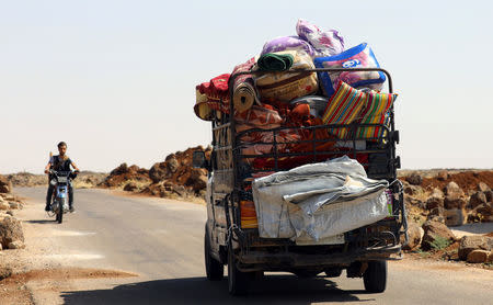 A man rides on a motorbike near a truck loaded with belongings in Deraa countryside, Syria June 22, 2018. REUTERS/Alaa al-Faqir