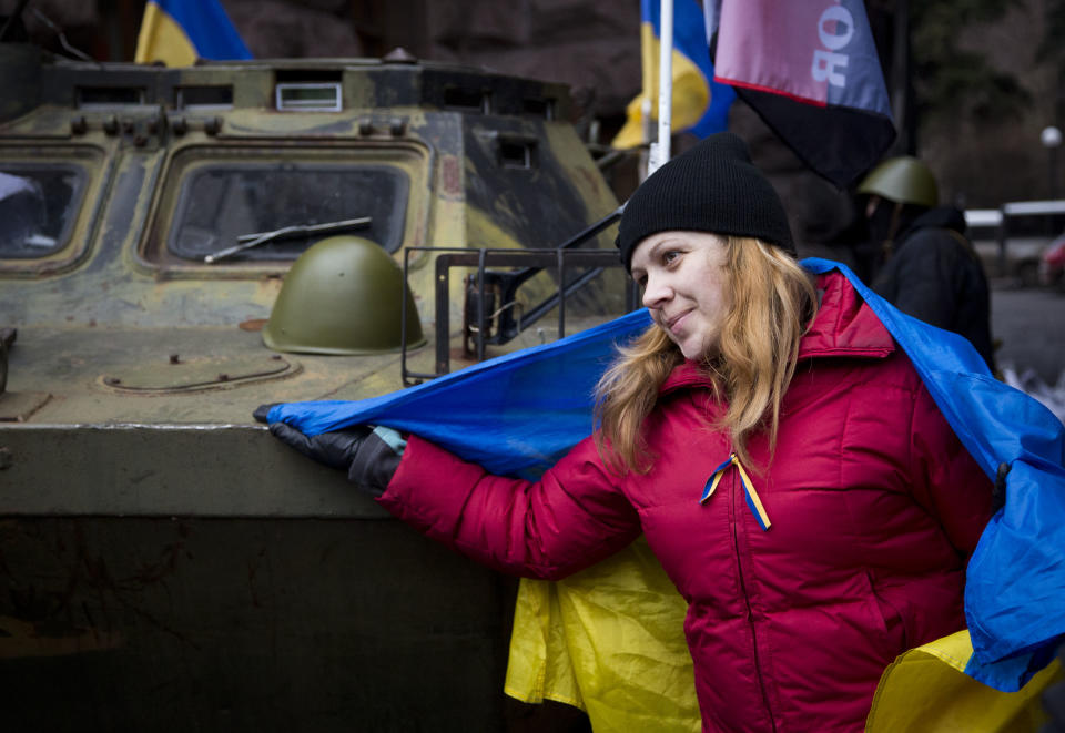 A protester poses next to an captured armored vehicle, in central Kiev, Ukraine, Saturday, Feb. 22, 2014. Protesters in the Ukrainian capital claimed full control of the city Saturday following the signing of a Western-brokered peace deal aimed at ending the nation's three-month political crisis. The nation's embattled president, Viktor Yanukovych, reportedly had fled the capital for his support base in Ukraine's Russia-leaning east. (AP Photo/Darko Bandic)