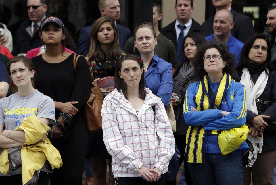 Heather McDade, de Boston, centro, mira con otros en un monitor gigante una ceremonia en honor de las víctimas del atentado contra el Maratón de Boston, en su primer aniversario, en la Calle Boylston, el martes 15 de abril de 2014, en Boston. (Foto AP/Steven Senne)