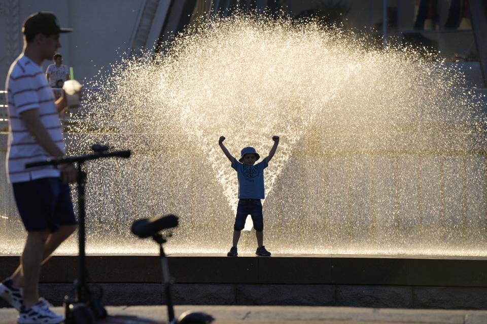 A boy plays in a fountain at VDNKh (The Exhibition of Achievements of National Economy) in Moscow, Russia, Sunday, June 20, 2021. The hot weather in Moscow is continuing, with temperatures forecast to reach over 30 degrees Celsius (86 Fahrenheit). (AP Photo/Alexander Zemlianichenko)
