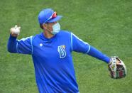 Yokohama DeNA BayStars coach wearing a protective face mask throws a ball amid the coronavirus disease (COVID-19) outbreak, in Yokohama, Japan