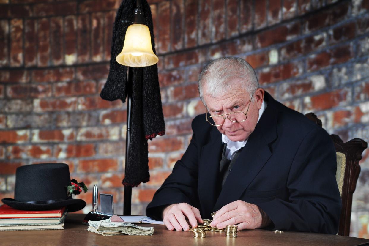 A grumpy old man scowling at the viewer as he counts his gold coins by a stack of large bills.