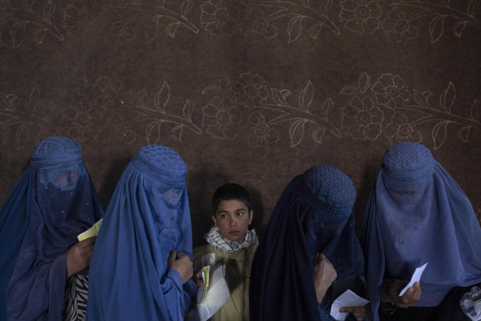 FILE - Afghan women wait to receive cash at a money distribution point organized by the World Food Program, in Kabul, Afghanistan, on Nov. 20, 2021. The United Nations is predicting that a record 274 million people – who together would amount to the world’s fourth most-populous country – will require emergency humanitarian aid next year in countries including Afghanistan, Ethiopia, Myanmar, Syria and Yemen as they face a raft of challenges such as war, insecurity, hunger, climate change and the coronavirus pandemic. (AP Photo/Petros Giannakouris)