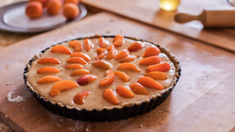 Unbaked frangipane and apricot tart on cutting board