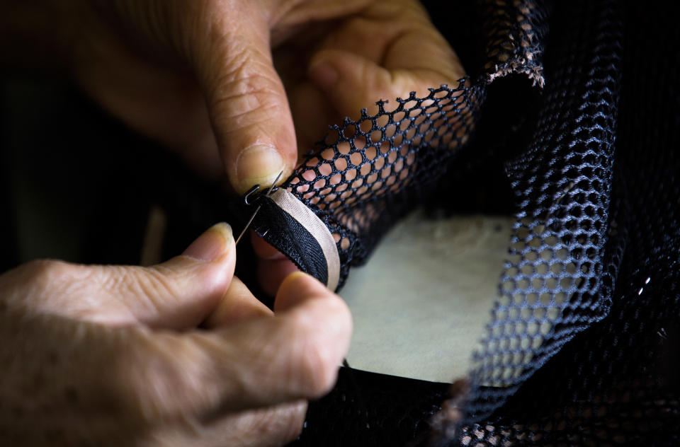 A worker stitches fabric in fashion designer Carmen Marc Valvo's New York studio, on Wednesday, Sept. 4, 2013. Valvo will show his Spring 2014 collection on Sept. 6 at Lincoln Center in New York. (AP Photo/John Minchillo)