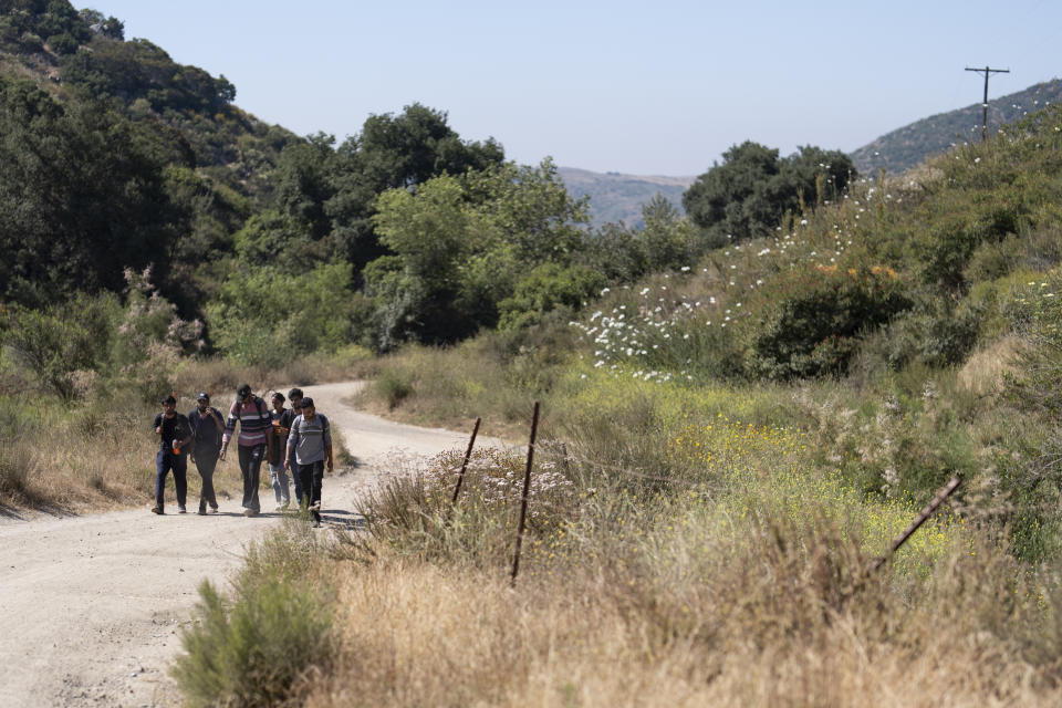 FILE - Migrants seeking asylum from India walk towards a staging area before being transported and processed, Wednesday, June 5, 2024, near Dulzura, Calif. President Joe Biden has suspended asylum processing at the U.S. border under a new policy unveiled this week. But the proclamation has an exception for “operational considerations.” The Homeland Security Department said in a detailed document outlining the ban that “demographics and nationalities encountered at the border significantly impact” its ability to deport people. (AP Photo/Gregory Bull, File)