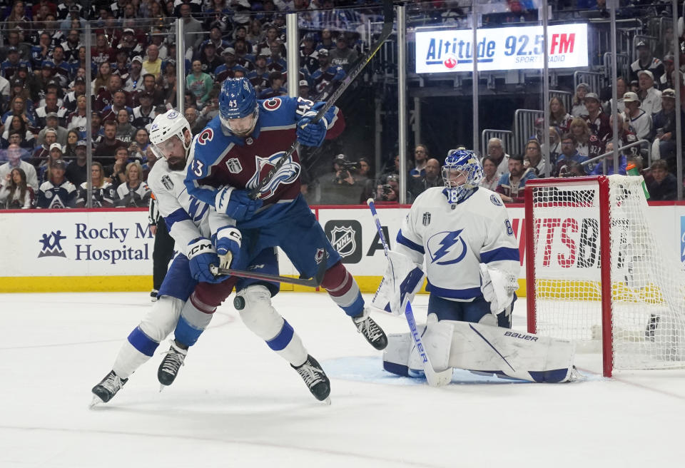 Tampa Bay Lightning left wing Nicholas Paul (20) and Colorado Avalanche center Darren Helm (43) tangle in front of Lightning goaltender Andrei Vasilevskiy (88) during the third period of Game 1 of the NHL hockey Stanley Cup Final on Wednesday, June 15, 2022, in Denver. (AP Photo/John Locher)