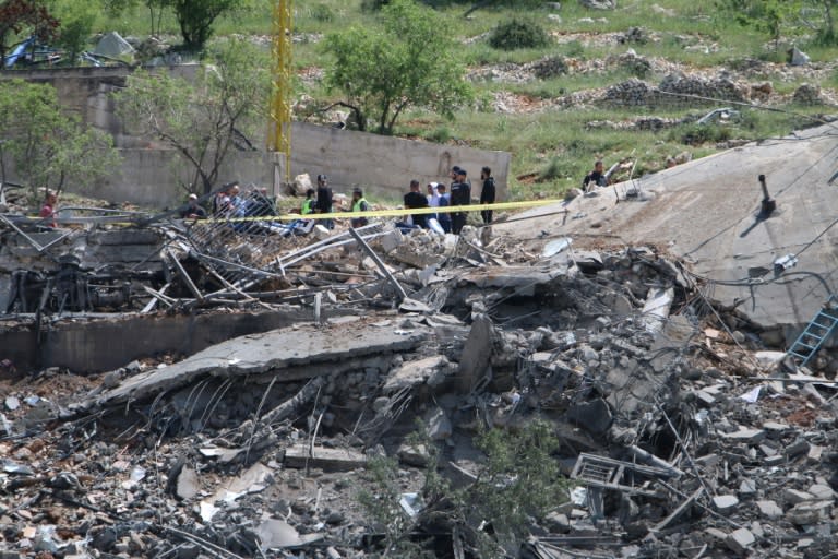 People gather around a destroyed building targeted by Israel in Lebanon's Baablbek district (-)