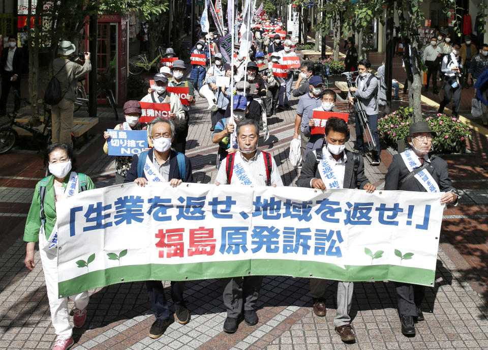 A group of plaintiffs and supporters march ahead of the Sendai High Court's ruling on the Fukushima Dai-ichi nuclear plant disaster in Sendai, northern Japan, Wednesday, Sept. 30, 2020. The court on Wednesday found negligence by the government and the operator of the wrecked Fukushima nuclear plant in failing to take tsunami measures to prevent the 2011 nuclear disaster, ordering them to jointly pay some 1 billion yen ($9.5 million) in damages to thousands of residents for their lost livelihoods. The banner reads: "Return jobs, return regions!" (Kyodo News via AP)