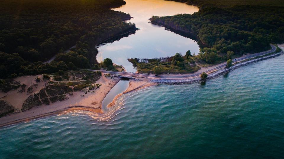 A bird's eye view of the Duck Lake Channel and Lake Michigan coastline in Muskegon County, seen shortly after sunrise. A tributary runs beneath the bridge on Scenic Drive near Whitehall.