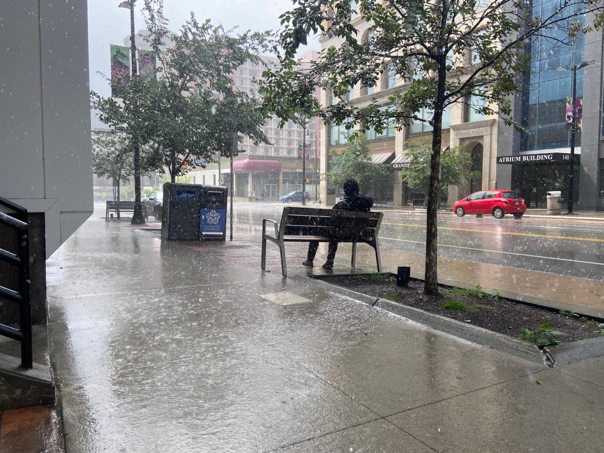 A man sits motionless getting soaked in the rain in downtown Rochester in 2023. There is a vulnerable population around the downtown district that spends time every day out on the streets or is unhoused.