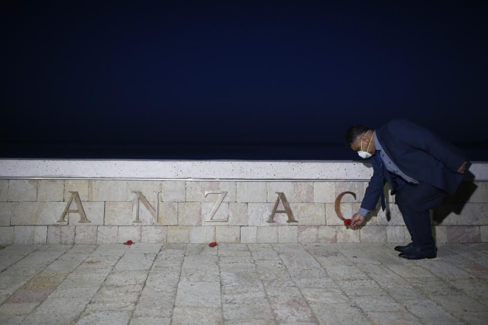 An employee of a local tourism company leaves a poppy at the Anzac Cove beach memorial in Gallipoli peninsula, the site of World War I landing of the ANZACs (Australian and New Zealand Army Corps) on April 25, 1915, in Canakkale, Turkey, early Saturday, April 25, 2020. The dawn service ceremony and all other commemorative ceremonies honoring thousands of Australians and New Zealanders who fought in the Gallipoli campaign of World War I on the ill-fated British-led invasion, were cancelled this year due to the new coronavirus pandemic. (AP Photo/Emrah Gurel)