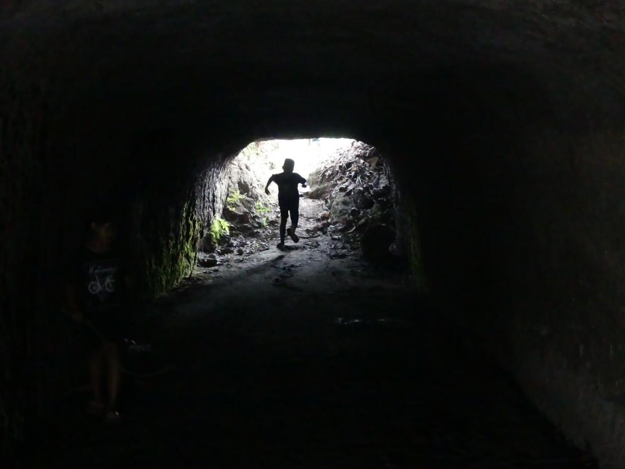 A child runs into the mouth of a cave that Japanese troops used to fight American troops in the Philippines.