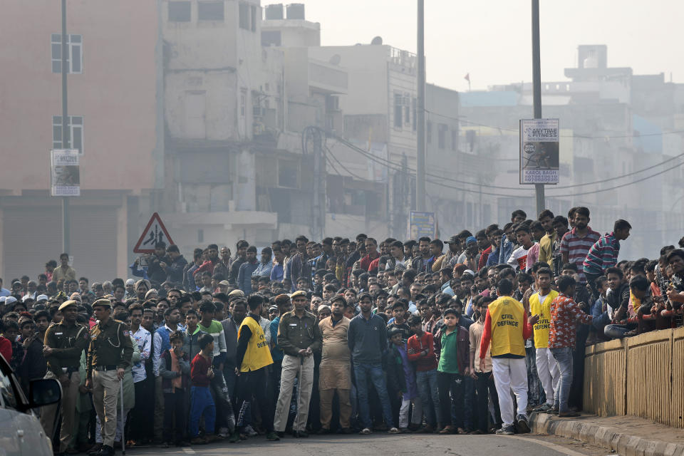 A crowd gathers near the site of a fire in New Delhi, India, Sunday, Dec. 8, 2019. Dozens of people died on Sunday in a devastating fire at a building in a crowded grains market area in central New Delhi, police said. (AP Photo/Manish Swarup)