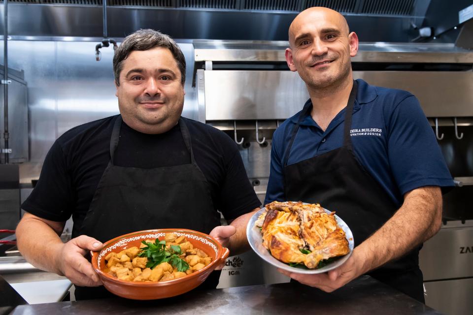 Mesa Moreira co-owner Steven Moreira (right) and Chef Eduardo Costa pose for a photo with two of the dishes they will serve at their new Portuguese restaurant (Picadinho de Porco and rotisserie barbecue chicken).