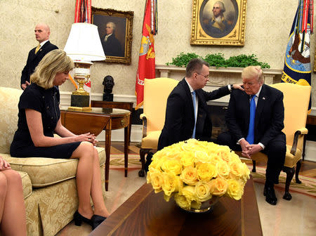 U.S. President Donald Trump closes his eyes in prayer along with Pastor Andrew Brunson, and his wife Norine, after his release from two years of Turkish detention, in the Oval Office of the White House, Washington, U.S., October 13, 2018. REUTERS/Mike Theiler