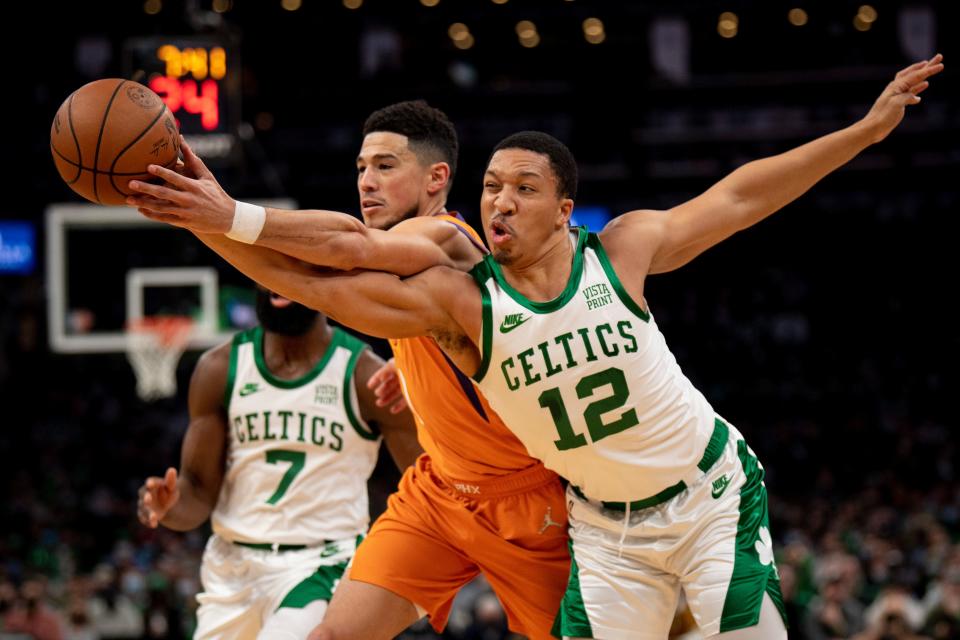 Phoenix's Devin Booker (center) and Boston's Grant Williams (12) battle for a loose ball during a Celtics' win earlier this season in Boston.