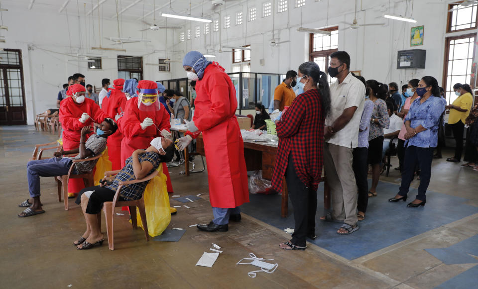 Sri Lankan health officials take swab samples from employees of the Colombo municipal council to test for COVID-19 in Colombo, Sri Lanka, Wednesday, Oct. 7, 2020. Authorities in Sri Lanka on Wednesday widened a curfew and warned of legal action against those evading treatment for COVID-19 after reporting an escalating cluster centered around a garment factory in the capital's suburbs. (AP Photo/Eranga Jayawardena)