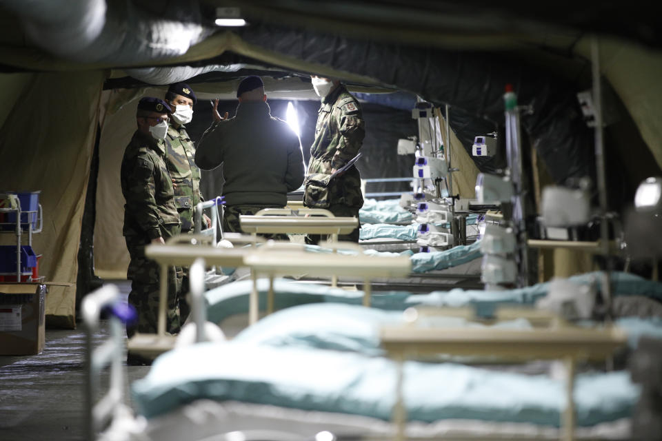 French soldiers discuss inside the military field hospital built in Mulhouse, eastern France, Monday March 23, 2020. The Grand Est region is now the epicenter of the outbreak in France, which has buried the third most virus victims in Europe, after Italy and Spain. For most people, the new coronavirus causes only mild or moderate symptoms. For some it can cause more severe illness. (AP Photo/Jean-Francois Badias)