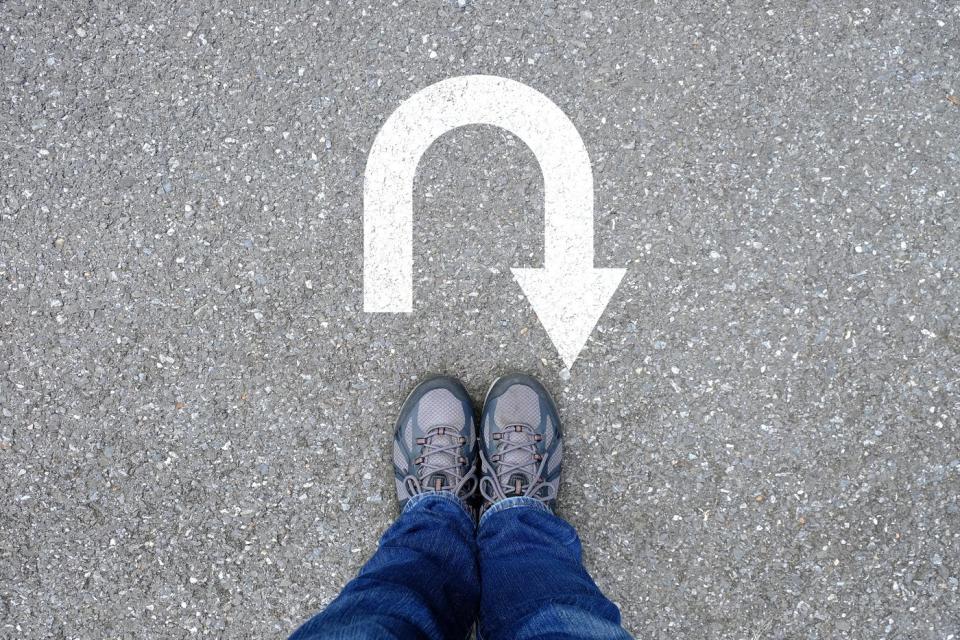 A person standing next to a U-turn arrow painted on the ground.