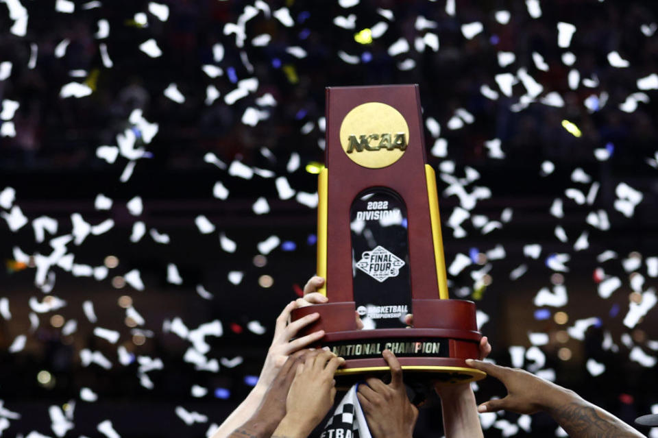 Athletes holding an NCAA trophy