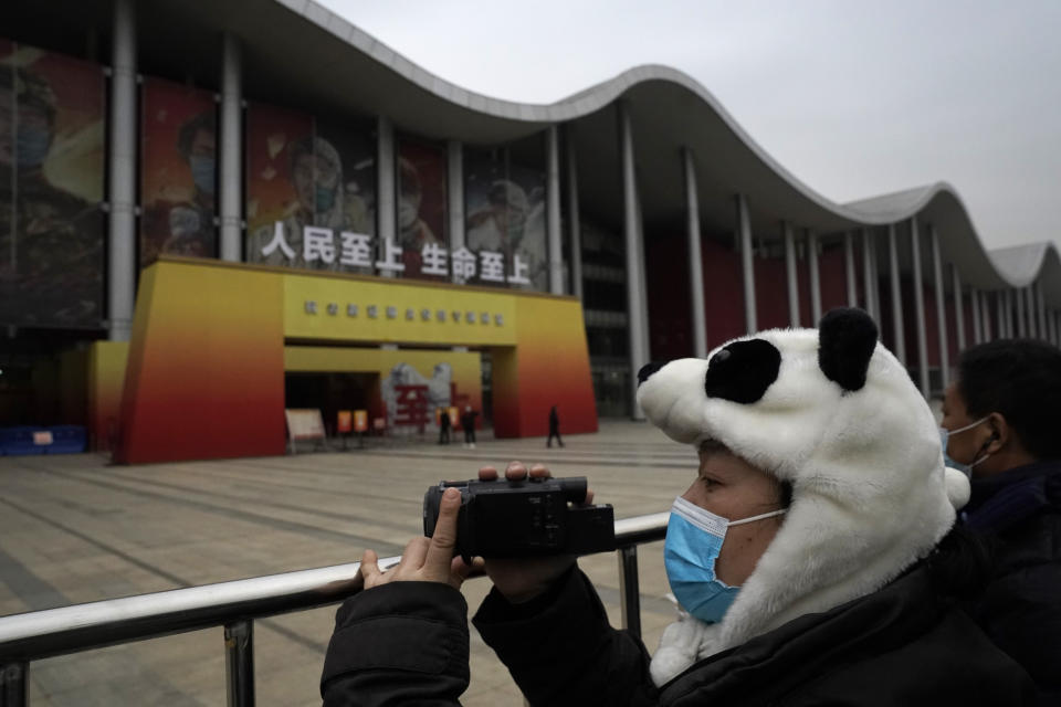 A journalist wearing a panda themed hat shoots with a camera outside an exhibition about the fight against the coronavirus when a World Health Organization team is visiting in Wuhan in central China's Hubei province on Saturday, Jan. 30, 2021. The World Health Organization team investigating the origins of the coronavirus pandemic visited another Wuhan hospital that had treated early COVID-19 patients on their second full day of work on Saturday. (AP Photo/Ng Han Guan)