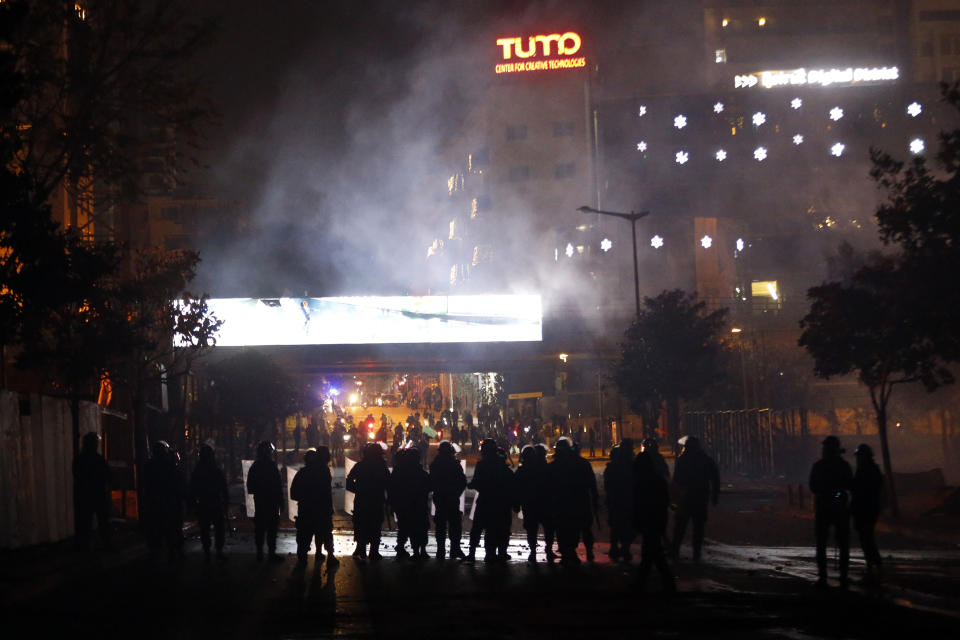 Lebanese riot police fire tear gas towards supporters of the Shiite Hezbollah and Amal groups in Beirut, Lebanon, Tuesday, Dec. 17, 2019. Supporters of Lebanon's two main Shiite groups Hezbollah and Amal have clashed with security forces and set fire to cars in Beirut in a third consecutive night of violence in the capital. The unrest early Tuesday apparently was triggered by a video circulating online that shows a man insulting Shiite and religious figures. (AP Photo/Bilal Hussein)